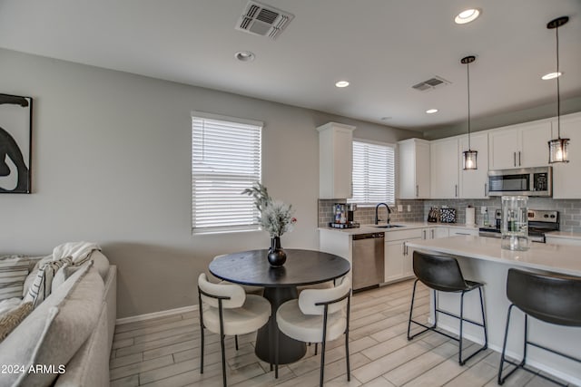 kitchen with stainless steel appliances, backsplash, and white cabinetry