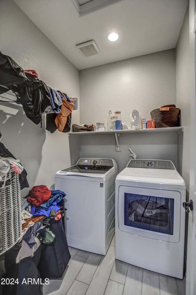 laundry area with light hardwood / wood-style flooring and washing machine and clothes dryer