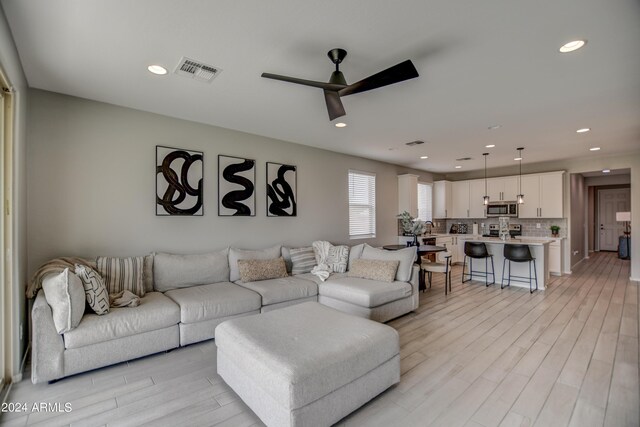 living room featuring light hardwood / wood-style floors and ceiling fan