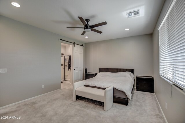 carpeted bedroom with a barn door and ceiling fan