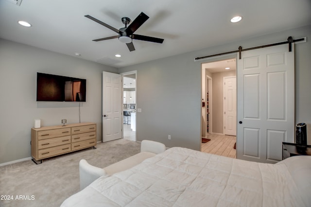 bedroom featuring a barn door, ceiling fan, and light colored carpet