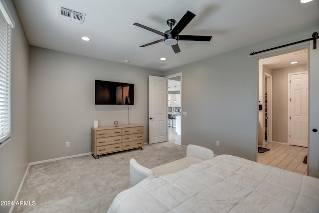 carpeted bedroom featuring a barn door and ceiling fan