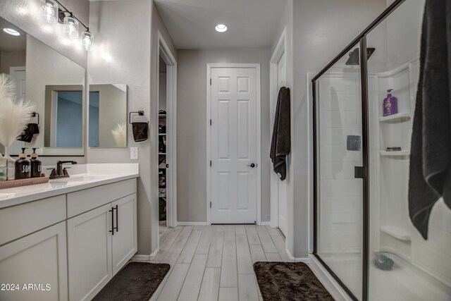 bathroom featuring walk in shower, large vanity, and wood-type flooring