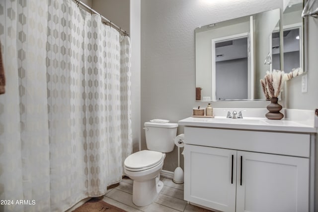 bathroom featuring tile floors, vanity, and toilet