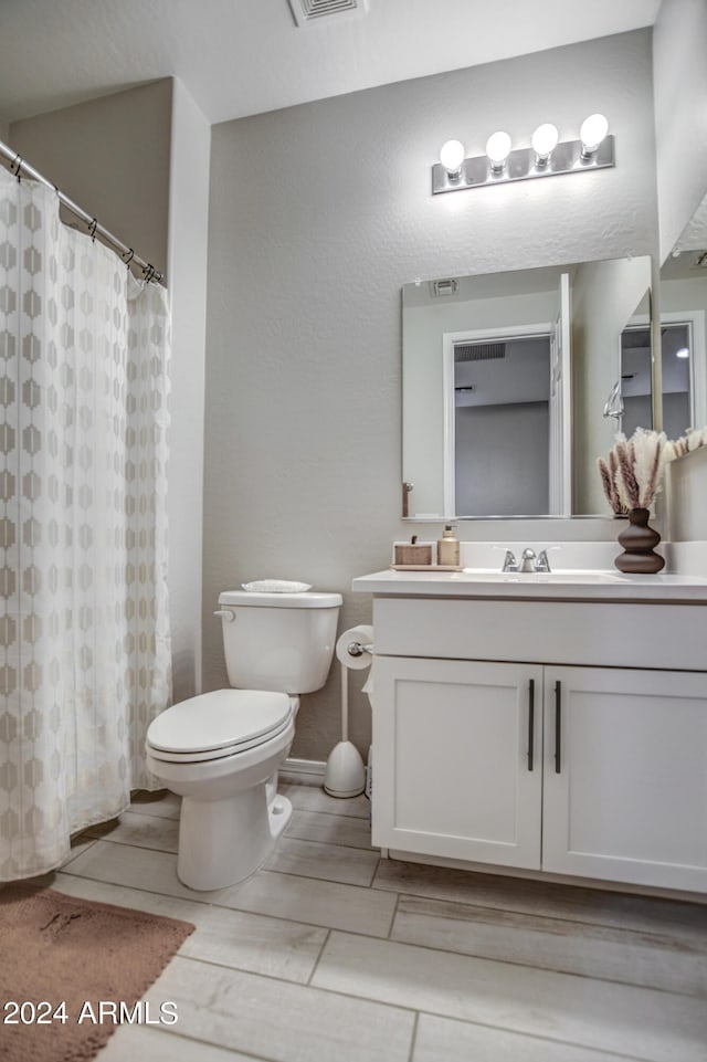 bathroom with tile flooring, toilet, and vanity