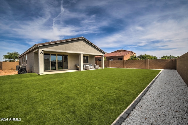 rear view of house with a lawn and a patio