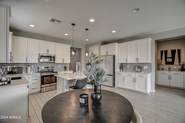 kitchen with backsplash, hanging light fixtures, a center island, appliances with stainless steel finishes, and sink