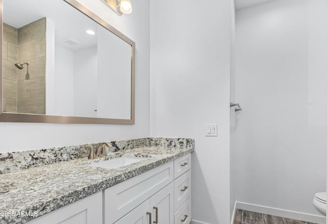 bathroom with vanity, toilet, tiled shower, and wood-type flooring