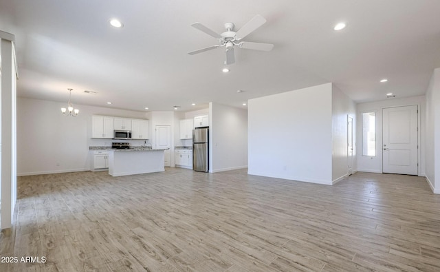 unfurnished living room with light hardwood / wood-style floors and ceiling fan with notable chandelier