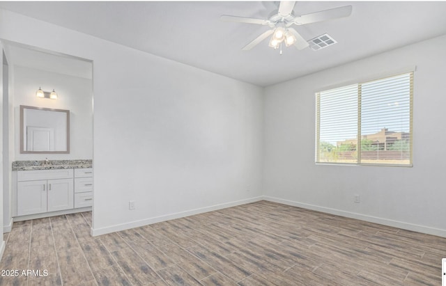 empty room with sink, light wood-type flooring, and ceiling fan