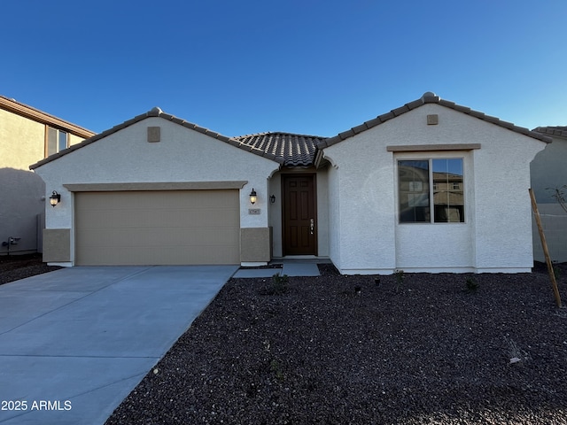 view of front of home with a tile roof, stucco siding, an attached garage, and concrete driveway