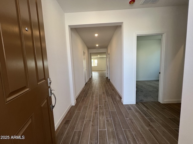 hall with wood finish floors, visible vents, and baseboards