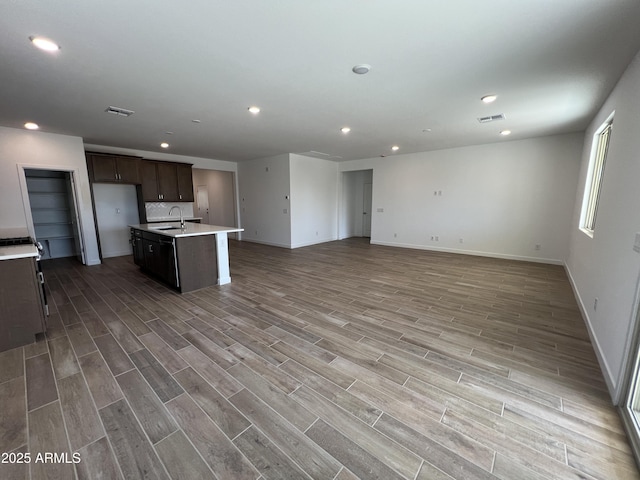 kitchen with visible vents, open floor plan, light wood finished floors, and a sink