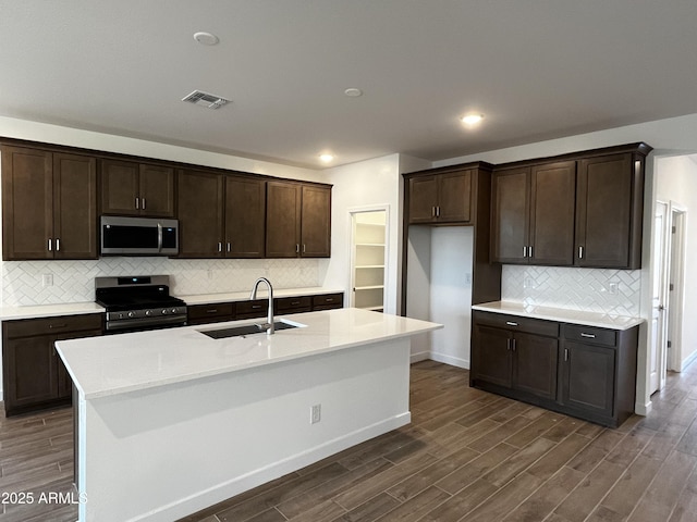 kitchen with visible vents, a sink, appliances with stainless steel finishes, dark brown cabinets, and dark wood-style flooring