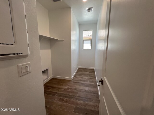 laundry area with baseboards, visible vents, and wood finish floors