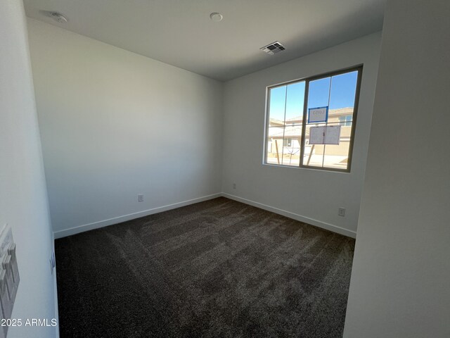 empty room featuring baseboards, visible vents, and dark carpet