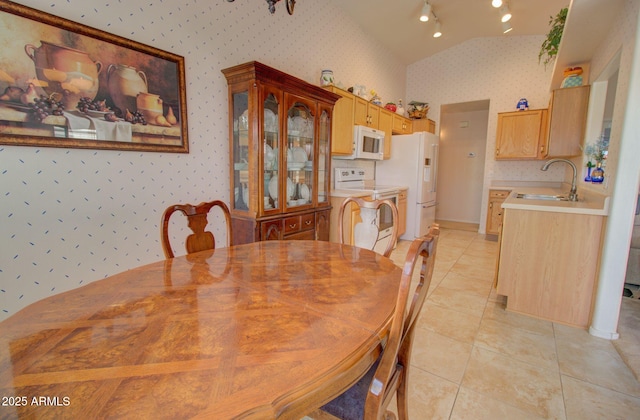 dining area featuring lofted ceiling, sink, and light tile patterned flooring