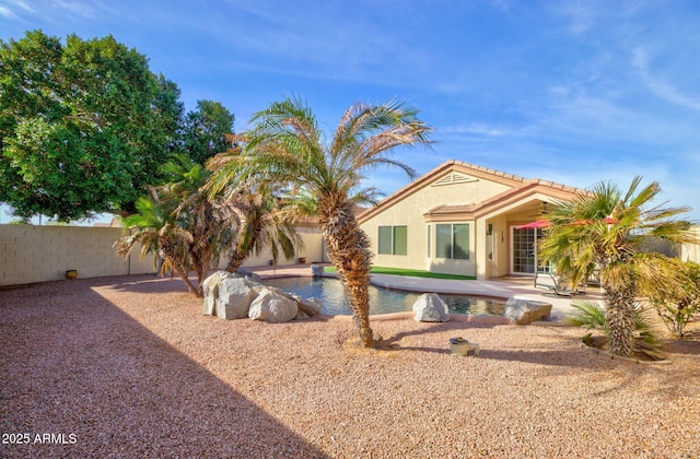 back of property with a fenced in pool and a patio