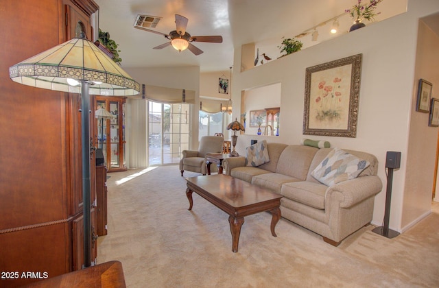 carpeted living room featuring vaulted ceiling, rail lighting, and ceiling fan with notable chandelier