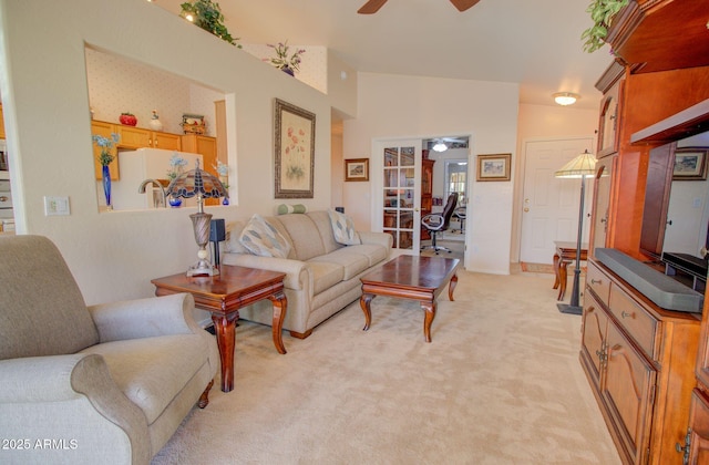 carpeted living room with ceiling fan and vaulted ceiling