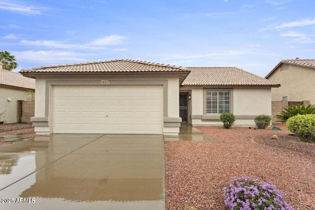 view of front of house featuring stucco siding, a tiled roof, driveway, and a garage