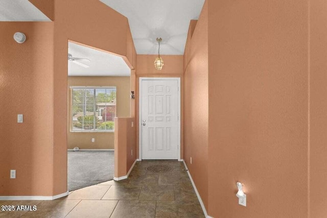 entryway featuring baseboards, arched walkways, and dark tile patterned floors