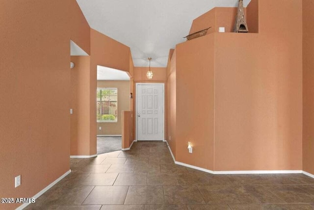 tiled entryway featuring baseboards and vaulted ceiling