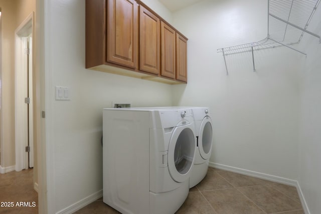 laundry area featuring washer and clothes dryer, light tile patterned flooring, and cabinets