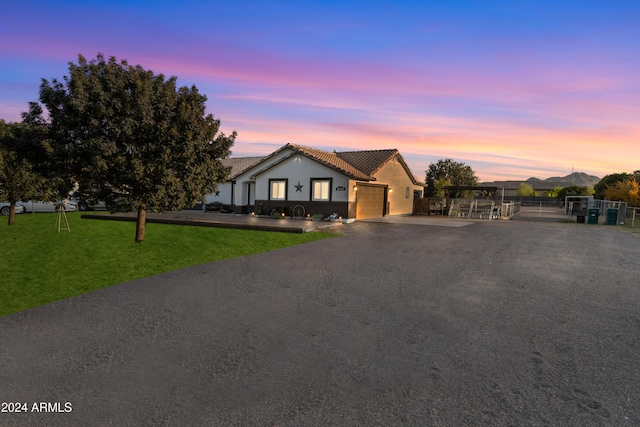 ranch-style home with stucco siding, fence, a garage, driveway, and a front lawn