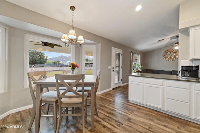 dining space featuring dark wood-type flooring, vaulted ceiling, baseboards, and ceiling fan with notable chandelier