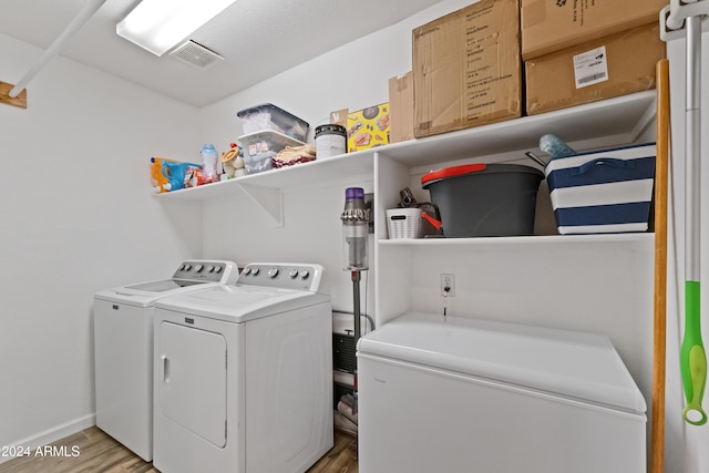 laundry area featuring washing machine and dryer, laundry area, visible vents, baseboards, and light wood-style floors