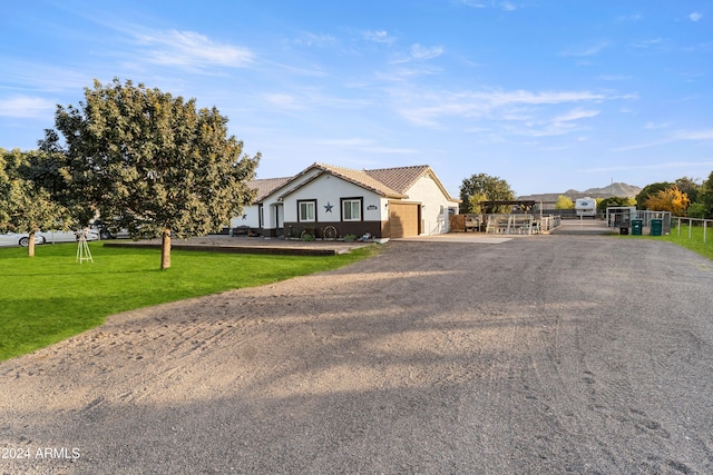 view of front facade with aphalt driveway, fence, a front lawn, and stucco siding