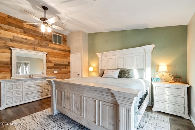 bedroom featuring lofted ceiling, visible vents, dark wood-type flooring, wood walls, and ceiling fan