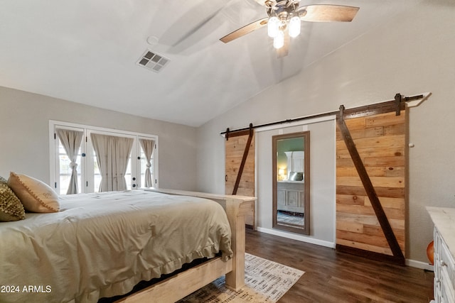 bedroom with lofted ceiling, a barn door, dark wood-type flooring, visible vents, and baseboards