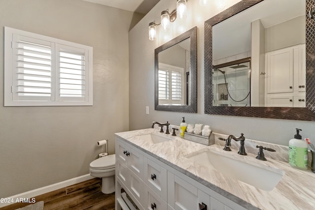 full bath featuring a stall shower, a sink, toilet, and wood finished floors