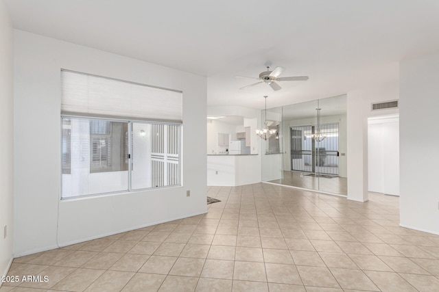 empty room with ceiling fan with notable chandelier and light tile patterned floors