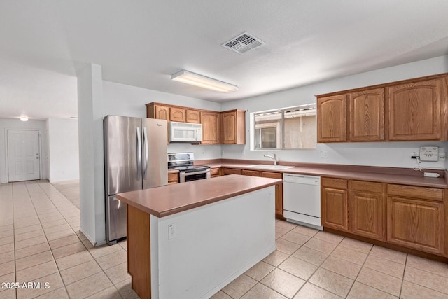 2421 W Romley Rd, Phoenix, AZ 85041 - kitchen with appliances with stainless steel finishes, light tile patterned floors, a sink, and a center island