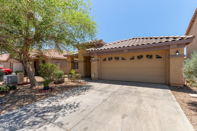2421 W Romley Rd, Phoenix, AZ 85041 - mediterranean / spanish-style home with stucco siding, concrete driveway, a tiled roof, and a garage