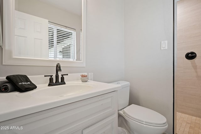 bathroom with tiled shower, toilet, and vanity