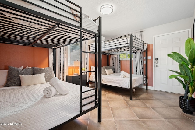 tiled bedroom with multiple windows, a textured ceiling, and baseboards