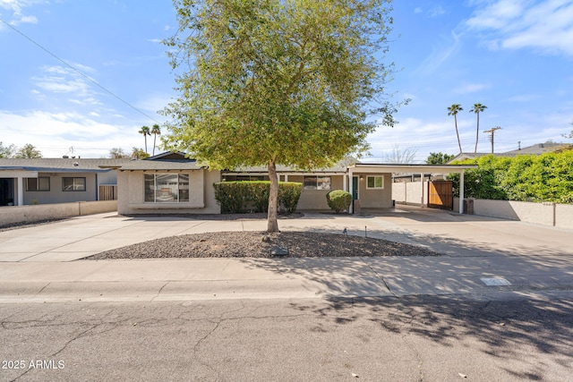 view of front of house featuring an attached carport, concrete driveway, and stucco siding