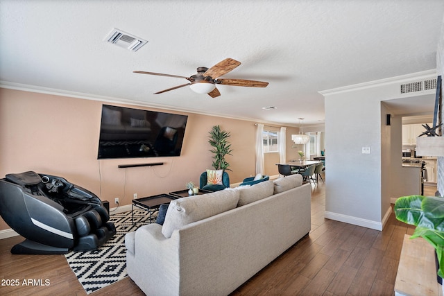 living room with baseboards, wood finished floors, visible vents, and ornamental molding