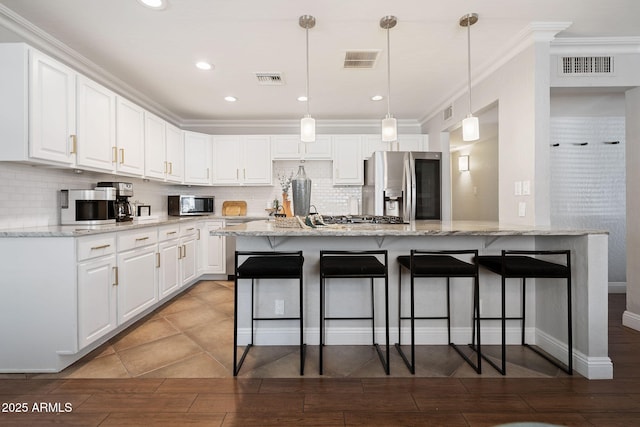 kitchen with white cabinets, a breakfast bar area, visible vents, and appliances with stainless steel finishes