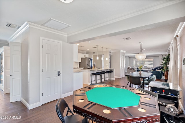 playroom with visible vents, baseboards, dark wood finished floors, and ornamental molding