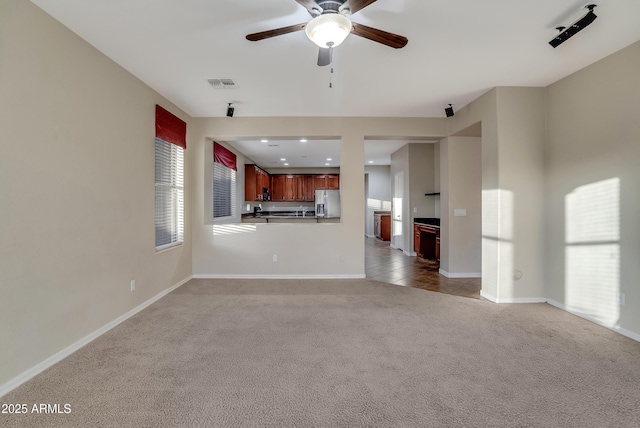 unfurnished living room featuring ceiling fan and light colored carpet