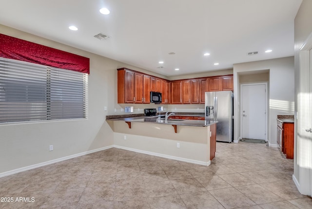 kitchen with range with electric cooktop, stainless steel fridge with ice dispenser, sink, a breakfast bar area, and kitchen peninsula