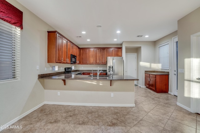 kitchen with sink, light tile patterned floors, a kitchen breakfast bar, black appliances, and kitchen peninsula