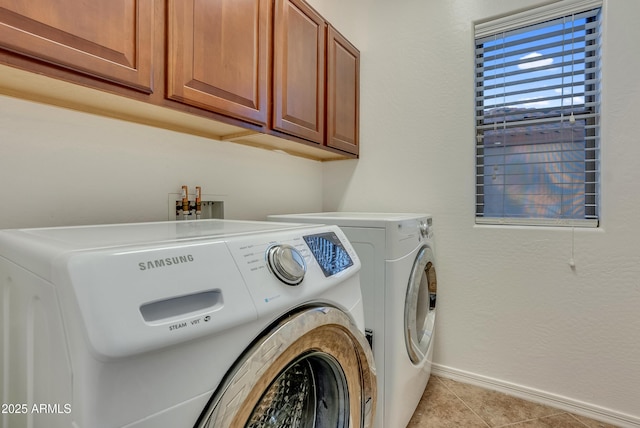 clothes washing area with light tile patterned floors, washing machine and dryer, and cabinets