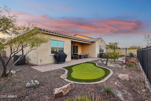 back house at dusk with central air condition unit and a patio