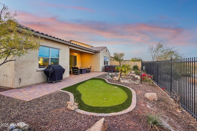 yard at dusk with a patio and a hot tub